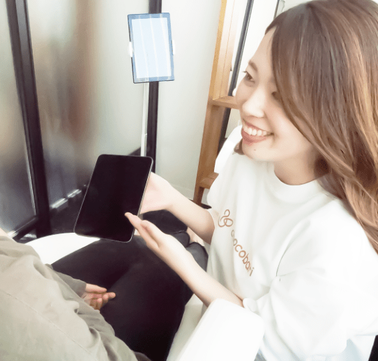 タブレットを見せながら笑顔でお客様に説明をする女性スタッフ