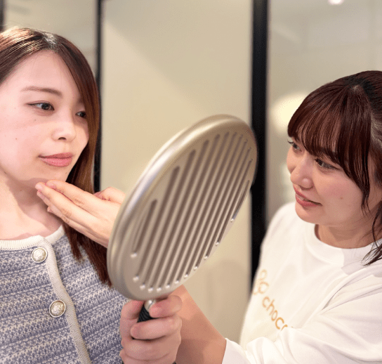 手鏡を見るお客様の顔に触れながら説明対応するスタッフ