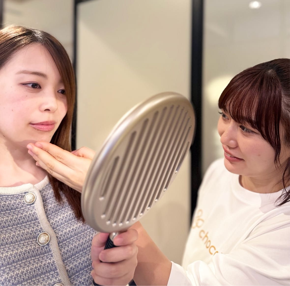 手鏡を見るお客様の顔に触れながら説明対応するスタッフ