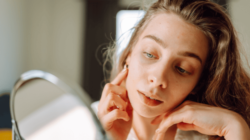 鏡で顔をチェックする女性