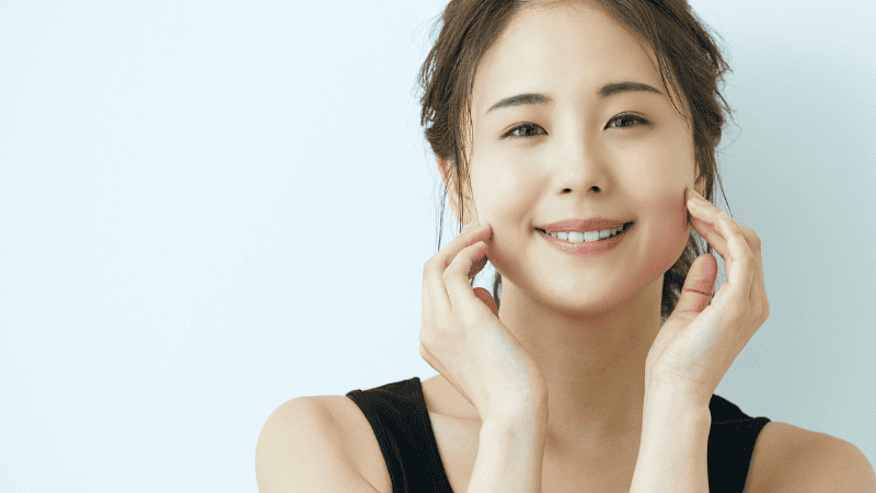 顔に手をそえて微笑む女性