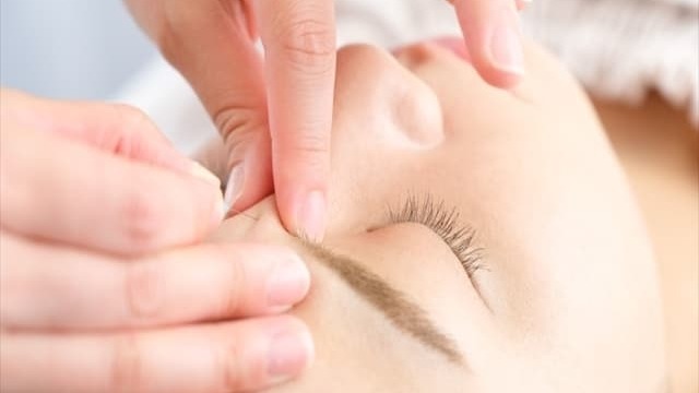 女性が顔に鍼治療を受けている