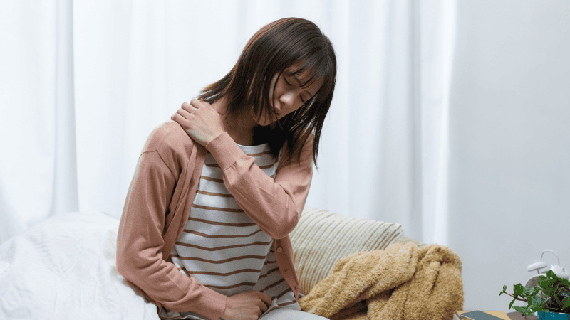 肩を抑える女性