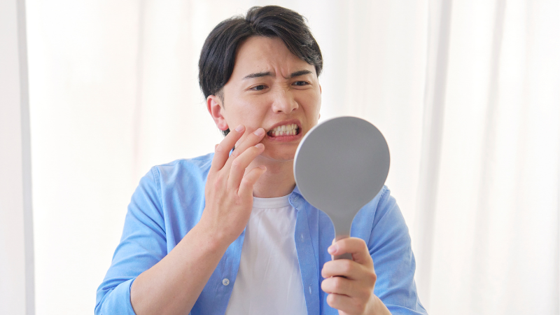 鏡で歯を見る男性