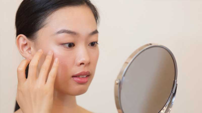 肌が気になって鏡を見る女性